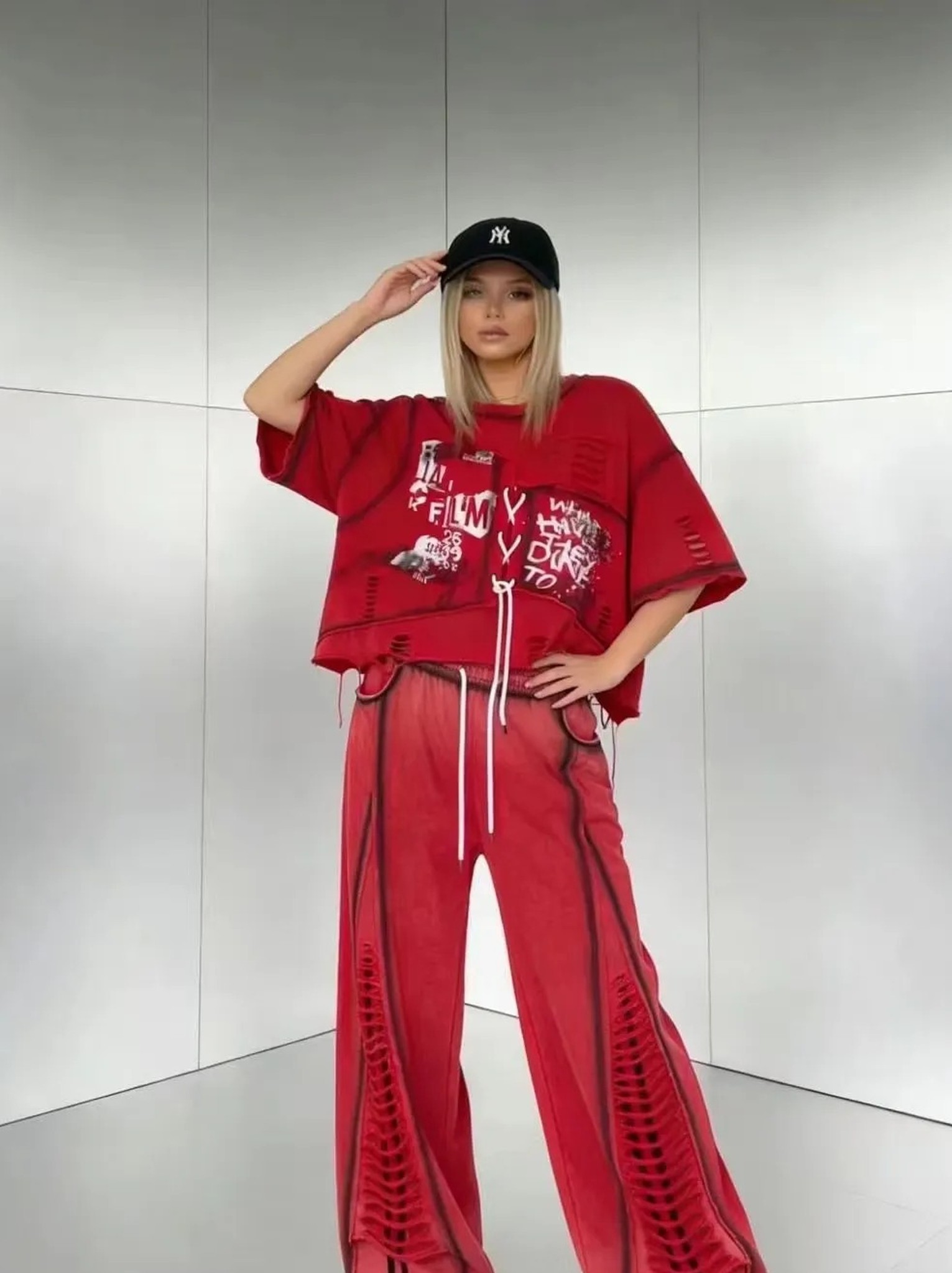 modelka w czerwonej bluzce oversize: nadruk z literami, kieszonka i sznurek przy dole