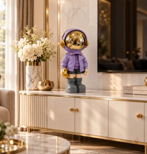 Figurka astronauty z żywicy ze złotym lustrzanym hełmem, 33 cm - salon glamour z szafką RTV w kolorze kości słoniowej, fioletowa figurka na blacie, ciepłe światło, skala 33 cm