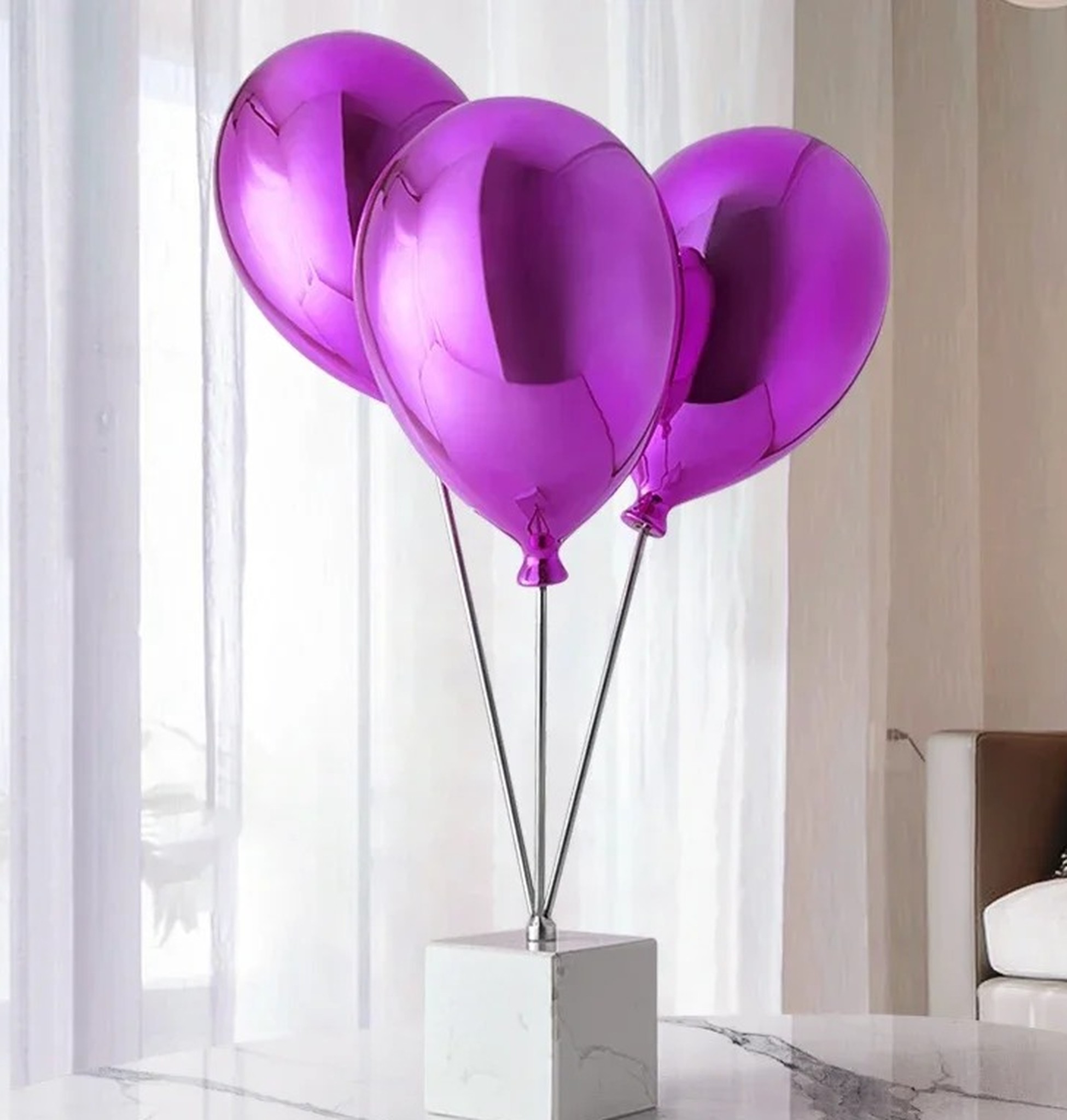 fioletowe balony na marmurowym blacie w jasnym wnętrzu z białymi zasłonami