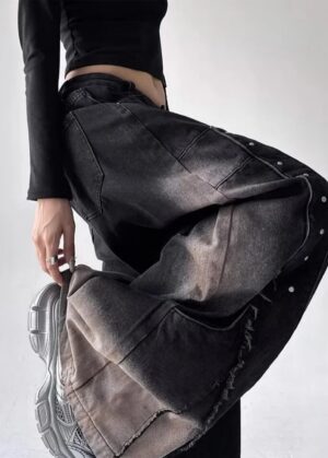Jeansy damskie baggy z nitami i cieniowaniem, szerokie nogawki - modelka w czarnych jeansach baggy w studiu z tłem w kolorze piasku, dynamiczna poza