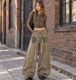 Jeansy damskie szerokie baggy z efektem sprania, retro, khaki - sesja na miejskiej ulicy z betonową ścianą, stylizacja z dopasowanym topem w kolorze oliwki i ciężkimi czarnymi butami
