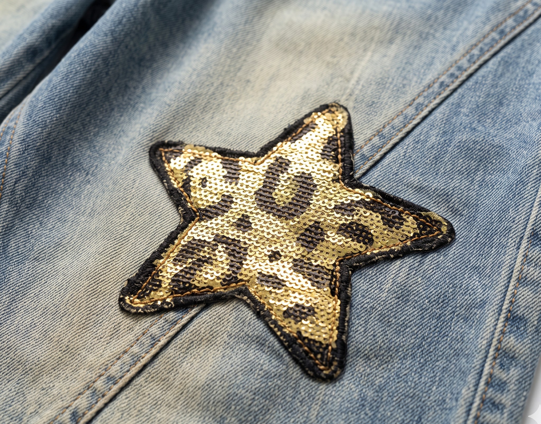 zbliżenie naszywki gwiazdy w cętki na udzie, sprany niebieski denim