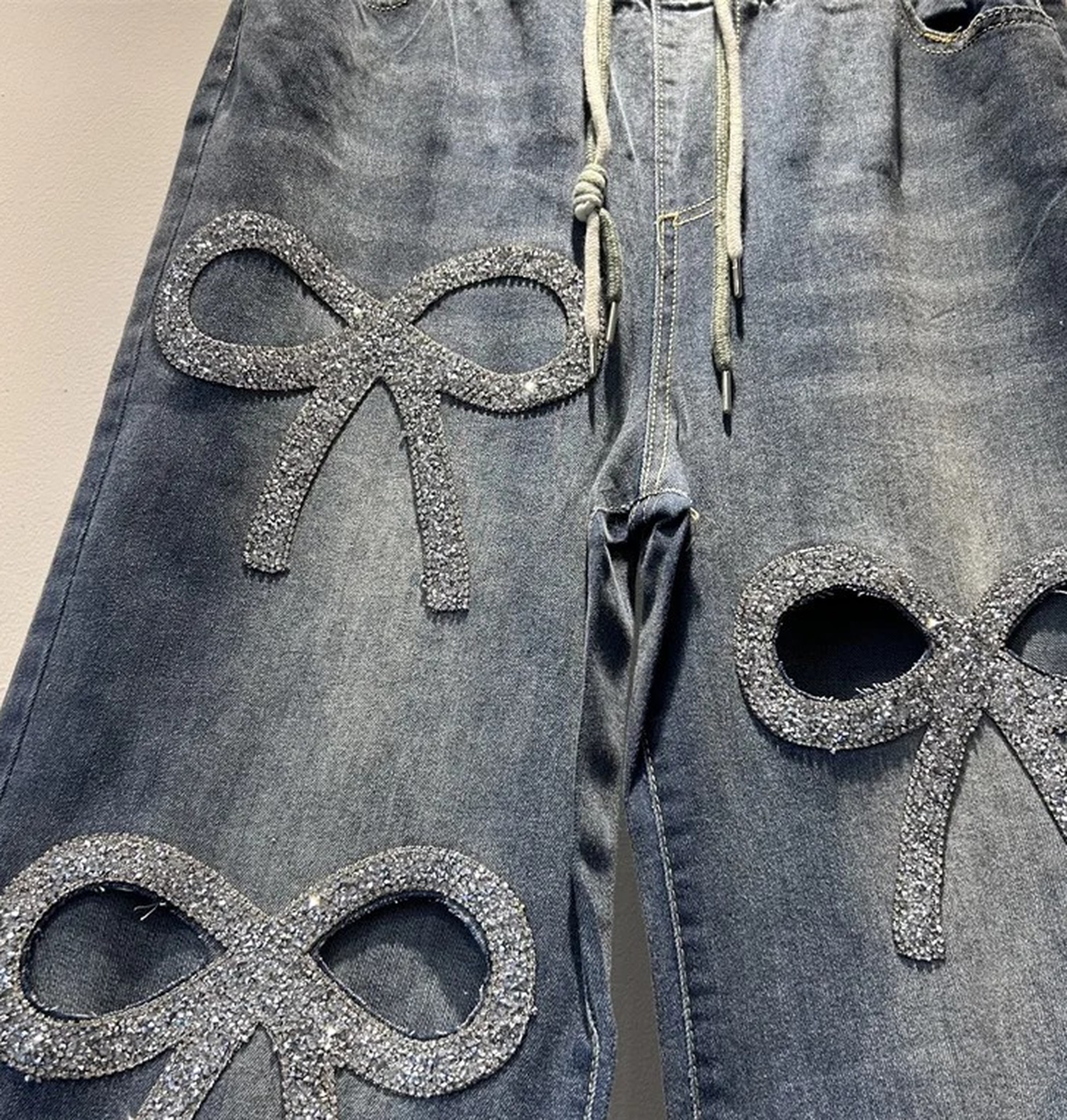 zbliżenie górnej części nogawek: cieniowany denim i dwie kokardy