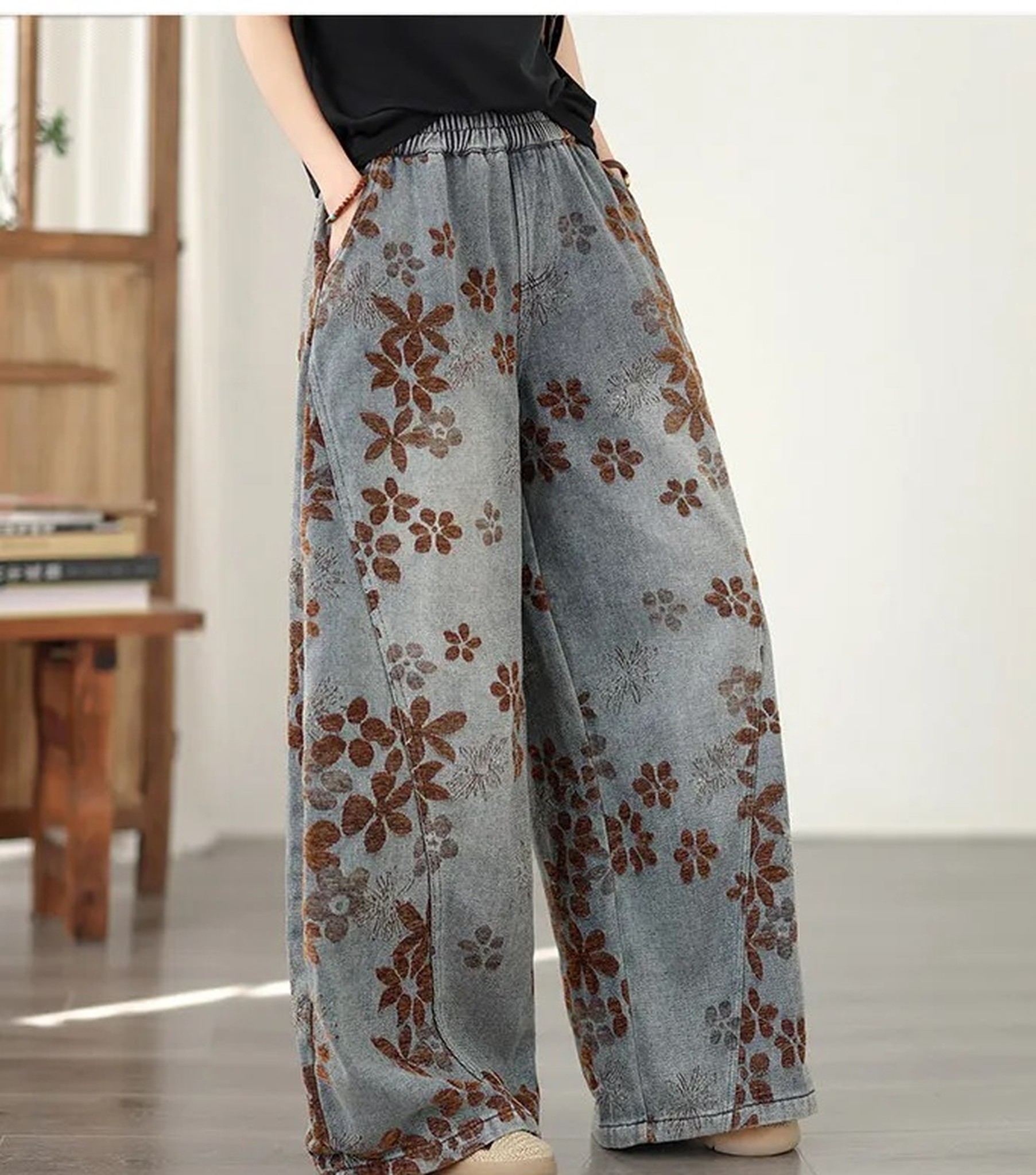 modelka w jeansach w kwiaty i czarnym T-shircie, dłoń w kieszeni