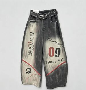 Jeansy damskie szerokie z nadrukiem w stylu graffiti, wysoki stan - modelka w czarnej wersji jeansów, skórzana ramoneska i ciężkie buty, industrialne wnętrze loftu, bez paska