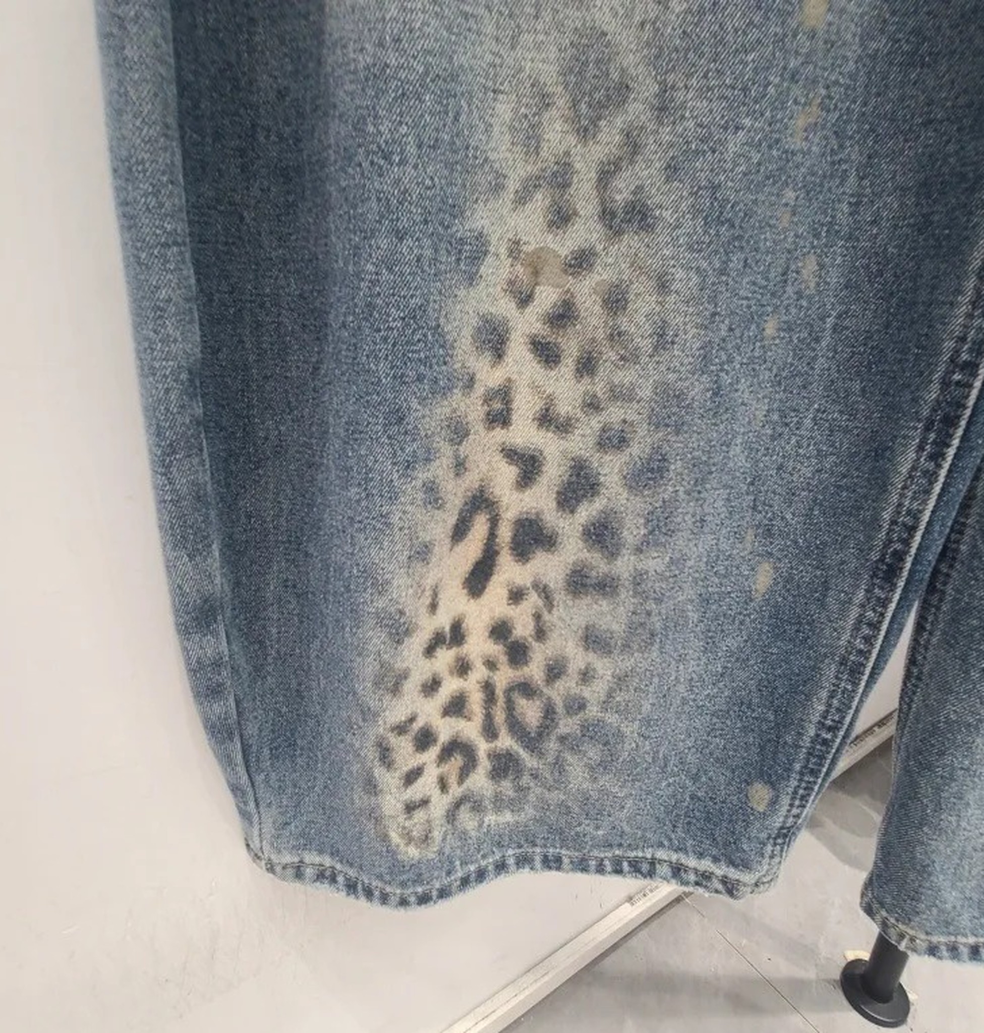 duże zbliżenie nadruku w panterkę przechodzącego w sprany denim na nogawce
