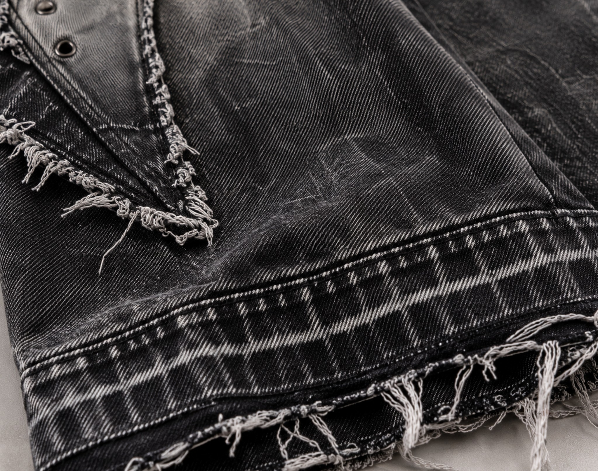 makro spranego czarnego denimu z postrzępionym brzegiem panelu i surowym dołem nogawki