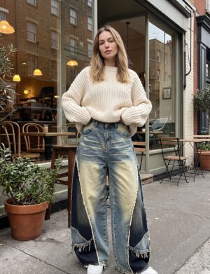 Jeansy damskie szerokie patchwork, wysoki stan, postrzępione brzegi - modelka przed kawiarnią, kremowy sweter, białe sneakersy