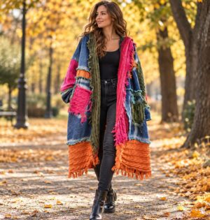 Kardigan damski patchwork z kapturem i frędzlami, oversize, dzianina - modelka w kardiganie w wersji niebieskiej z kapturem, jesienny park, czarne jeansy i botki