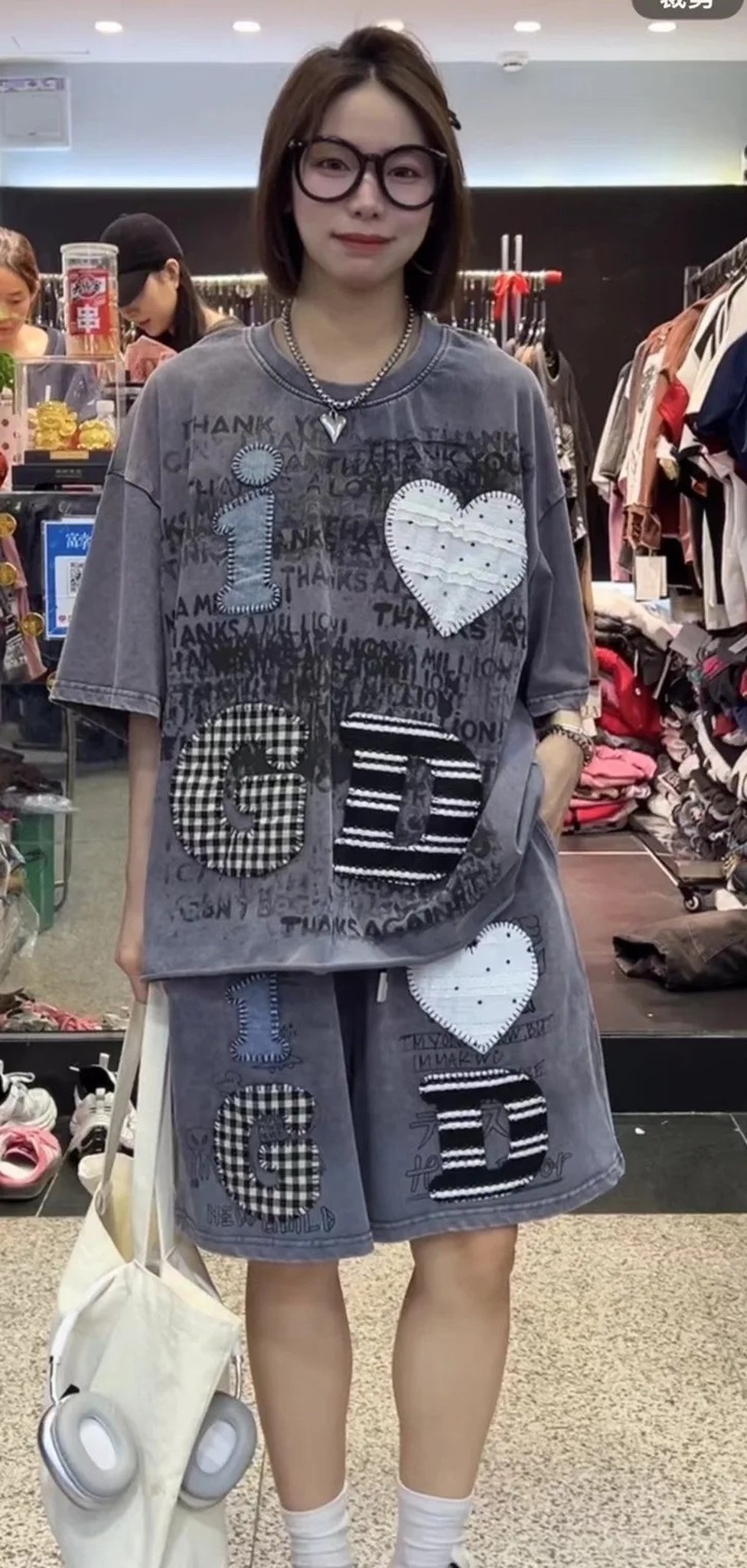 kobieta w szarym komplecie: luźny T-shirt i szorty do kolan, cała sylwetka