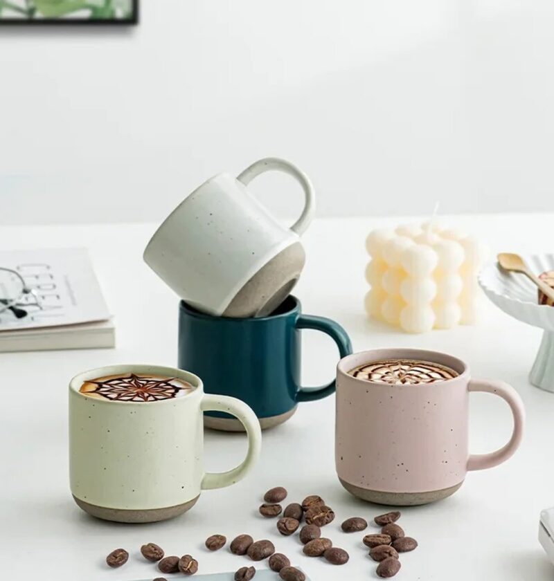 Kubek ceramiczny w kropki 150 ml, matowy, z surowym spodem - jasny stół z kawą latte, świecą i ziarnami kawy