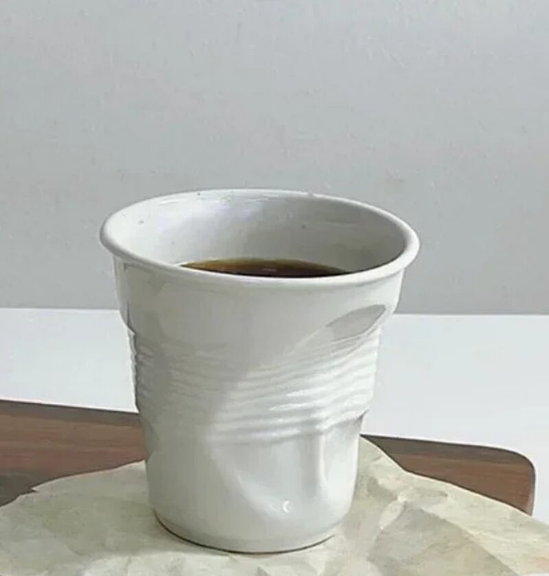 Kubek ceramiczny zgnieciony 200 ml, biały, do kawy i espresso - gładki kubek z kawą na stole