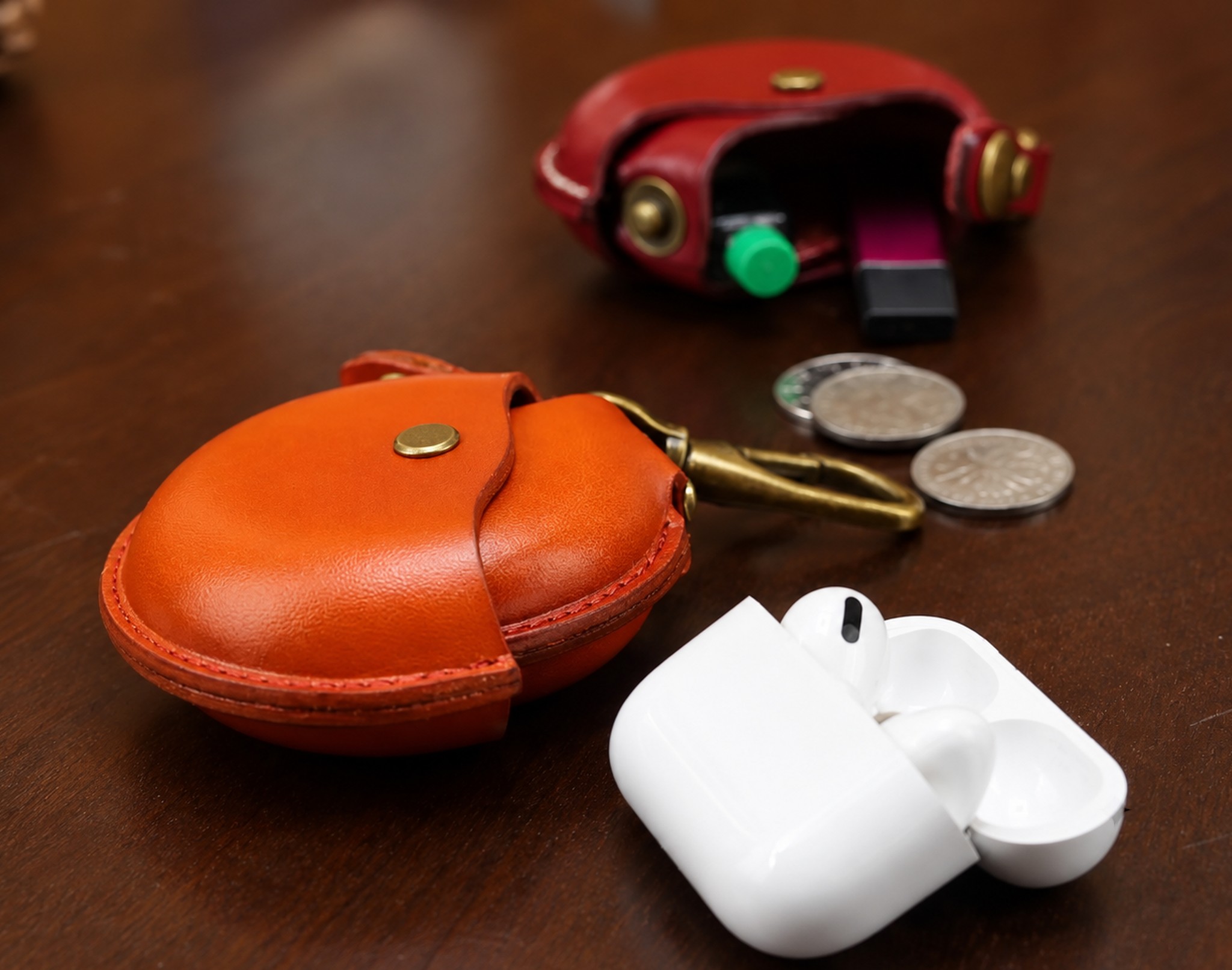 otwarte etui obok monet, słuchawek w etui ładującym i pendrive'a, bez napisów
