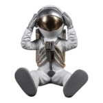 Figurka siedzącego astronauty, dekoracja z dłońmi przy hełmie