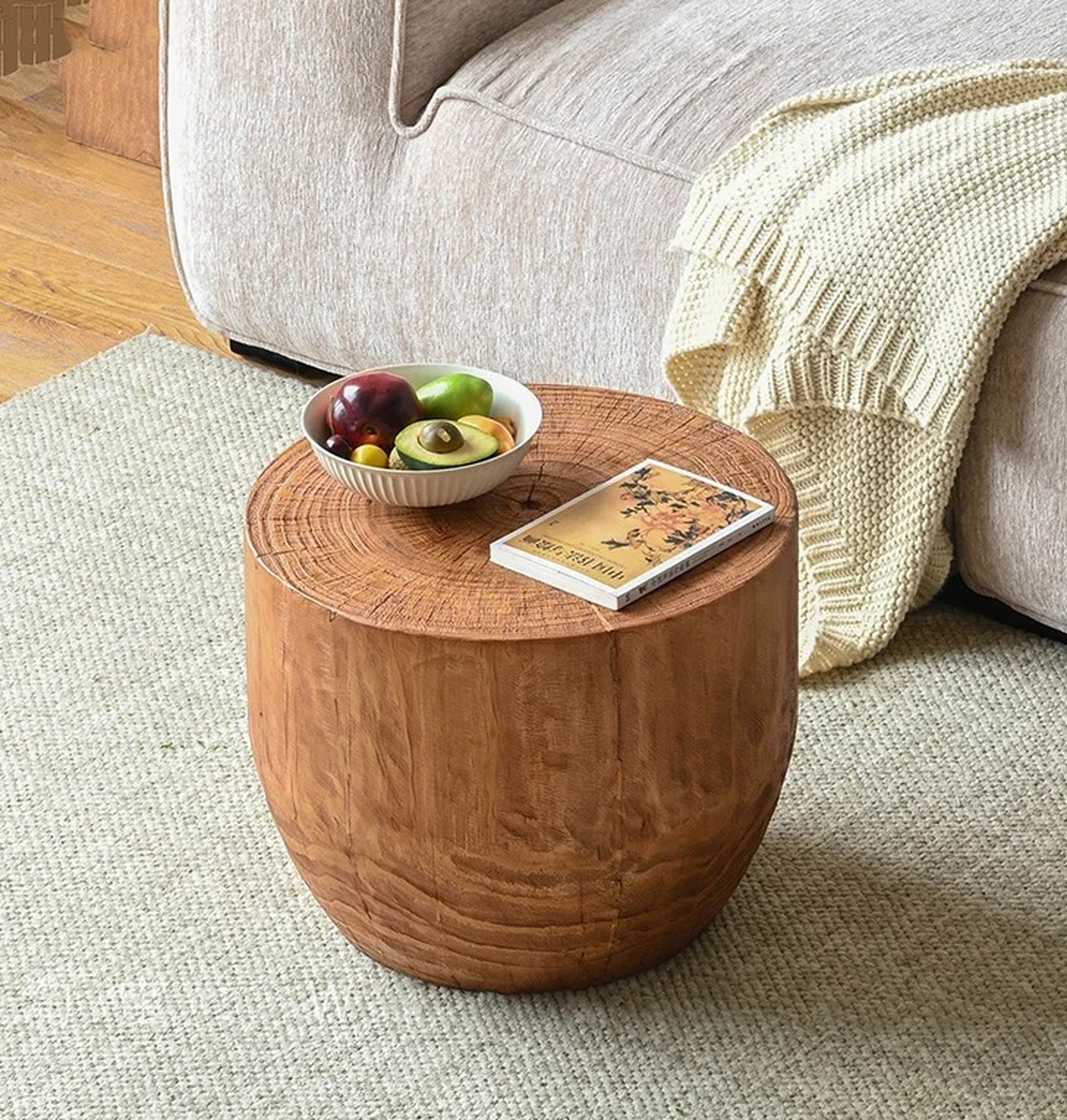 naturalny stolik 50 cm przy beżowej sofie z misą owoców i książką