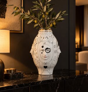 Wazon ceramiczny z twarzami 50 cm, biały z rysunkami i złotem - nowoczesny salon z ciemną ścianą i ciepłym światłem, wazon z gałązką oliwną
